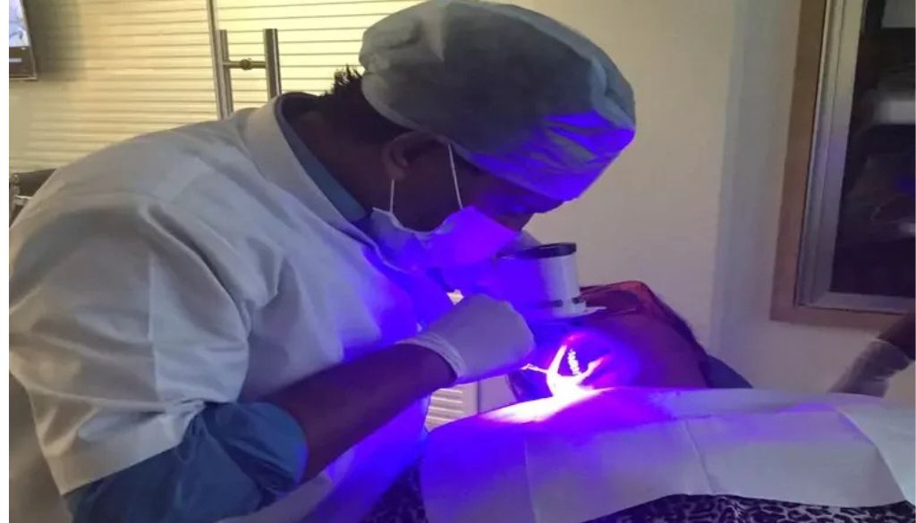 Generate an image of a dentist using Velscan technology for oral cancer screening.